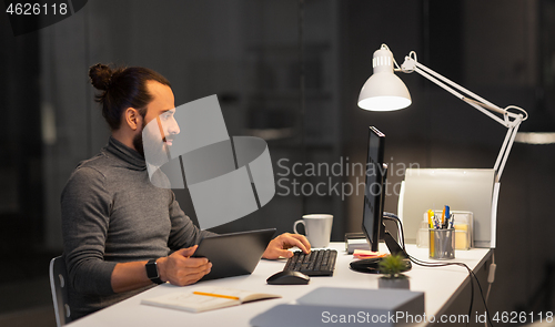 Image of creative man with computer working at night office