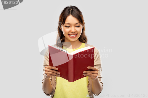 Image of happy asian woman reading book