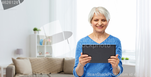 Image of senior woman using tablet computer at home