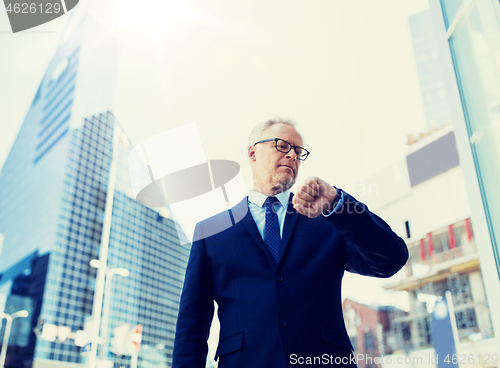 Image of senior businessman checking time on his wristwatch