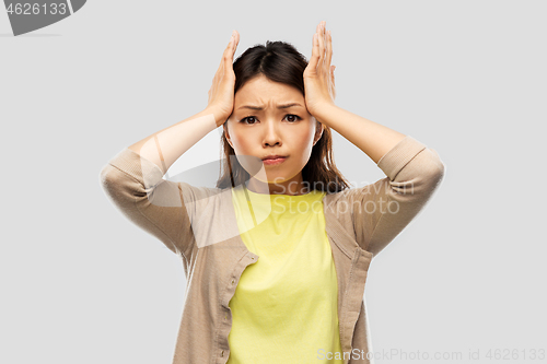 Image of stressed asian woman holding to her head