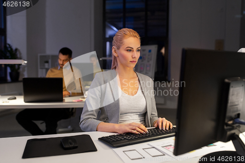 Image of designer working on computer at night office