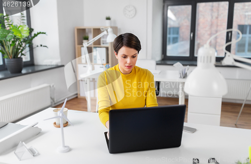 Image of businesswoman with laptop working at office