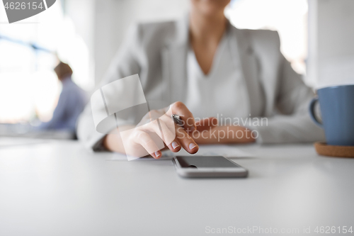 Image of hand of businesswoman using smartphone at office