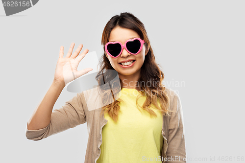 Image of asian woman in heart-shaped sunglasses waving hand