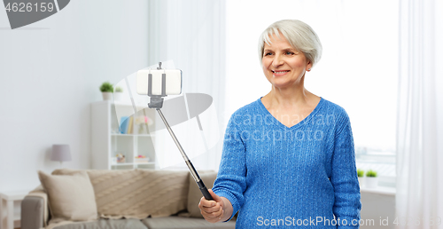 Image of smiling senior woman taking selfie by smartphone