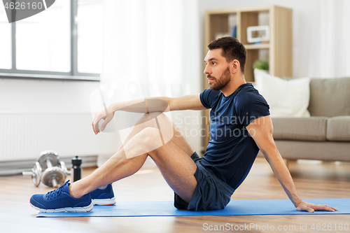 Image of man resting on exercise mat at home