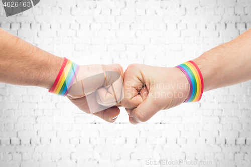 Image of hands with gay pride wristbands make fist bump