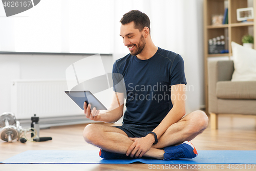 Image of man with tablet computer on exercise mat at home