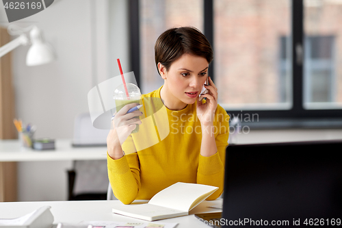 Image of woman with drink calling on smartphone at office