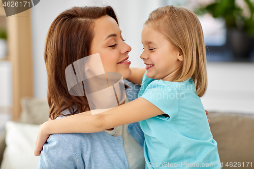 Image of little daughter hugging her mother on sofa at home