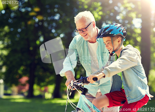 Image of grandfather and boy with bicycle at summer park