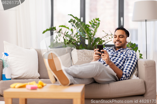 Image of indian man in headphones after cleaning home