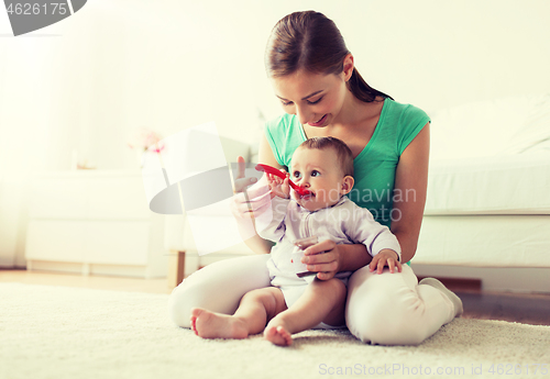 Image of mother with spoon feeding little baby at home