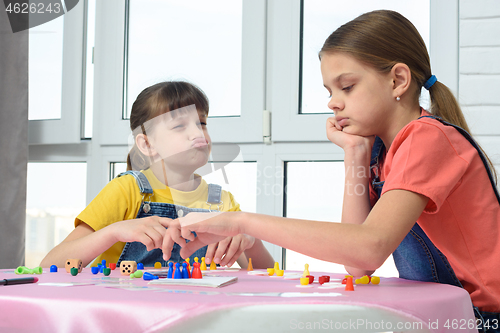 Image of Girl playing a board game teases another girl