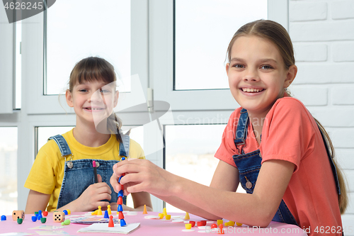 Image of Two happy girls play a board game and looked at the frame