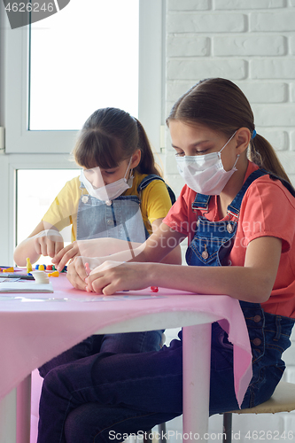 Image of Two sisters in medical masks play board games