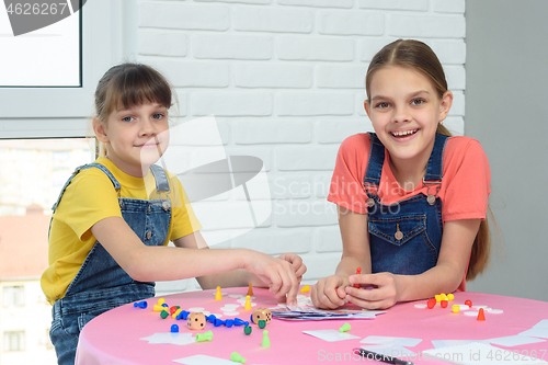 Image of Two girls play a board game and looked at the frame