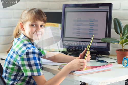 Image of student at home at a computer table with a tablet in his hands