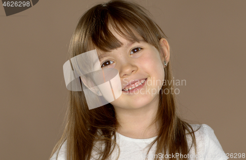 Image of Portrait of a little cute 7 year old girl in a white tshirt, posing and smiling