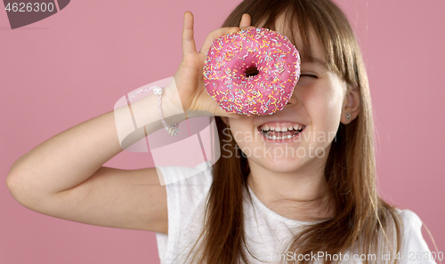 Image of Young beautiful happy and excited blond girl 6 or 7 years old holding donut on her eyes