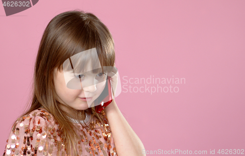 Image of Cheerful little blonde kid girl 6-7 years old in sequin dress talking on mobile phone.