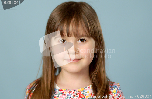 Image of Potrait of nice smiling little girl with logng hair posing over blue background in studio