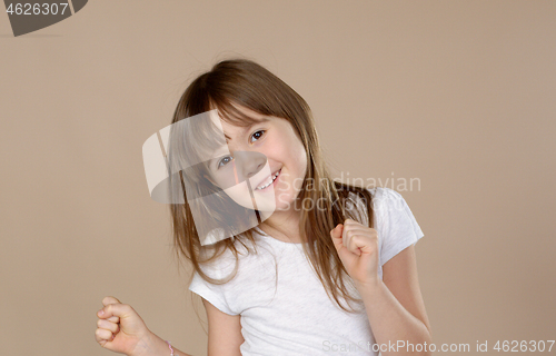 Image of Cute little girl in white tshirt dancing, smiling and having fun in studio session