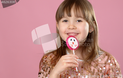 Image of Young happy, smiled, pretty little girl with sweet lollypop candy. Standing in sequined dress