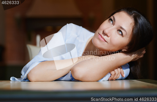 Image of Serious staying at home woman laying on the table