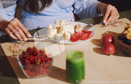 Image of Vegetarian woman sitting at the table and eating healthy food