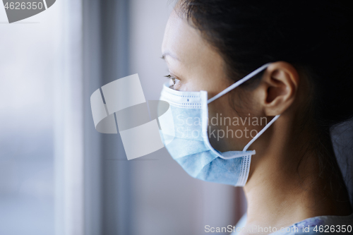 Image of Woman staying at home and wearing protective surgical mask