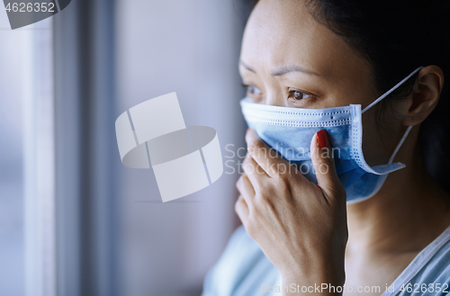 Image of Woman staying at home wearing protective surgical mask