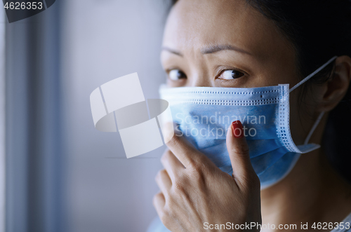 Image of Woman staying at home wearing protective surgical mask