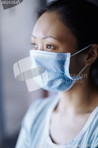 Image of Woman staying at home wearing protective surgical mask