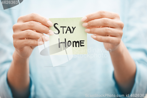 Image of Woman holding adhesive note with Stay Home text