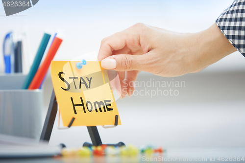 Image of Human hand holding adhesive note with Stay Home order