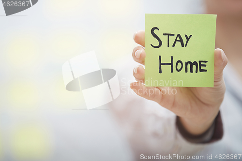 Image of Hand holding sticky note with Stay Home text