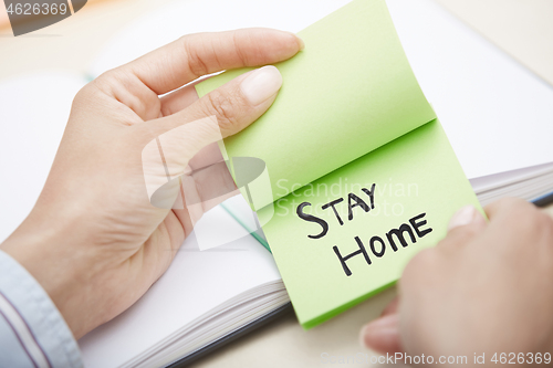 Image of Hands holding sticky note with Stay Home text