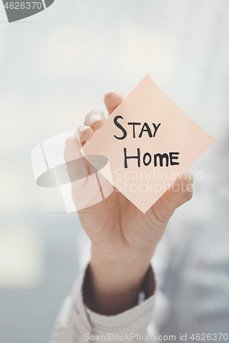 Image of Hand holding sticky note with Stay Home text