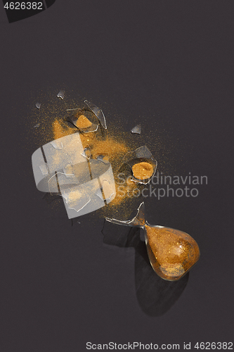Image of Cracked sandglass with golden sand on a dark background.