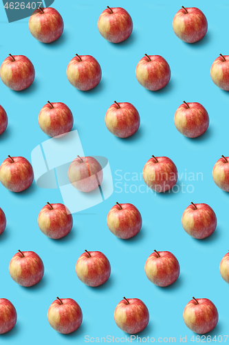 Image of Creative pattern from fresh organic red apples on a blue background.