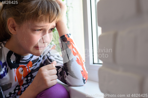 Image of Upset girl crying sitting by the window