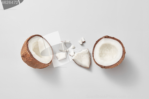 Image of Two halves of fresh natural organic coconut fruit on a light grey background.