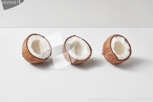 Image of Set from three tropical natural halves of coconut on a light grey background.