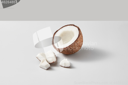 Image of Fresh half of ripe organic tropical coconut fruit on a light grey background.
