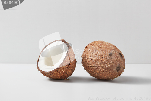 Image of Half and whole natural organic coconut fruits on a duotone grey background.