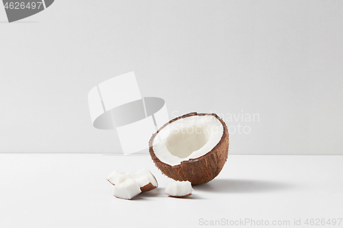 Image of Half of fresh ripe tropical coconut fruit on a light grey background.