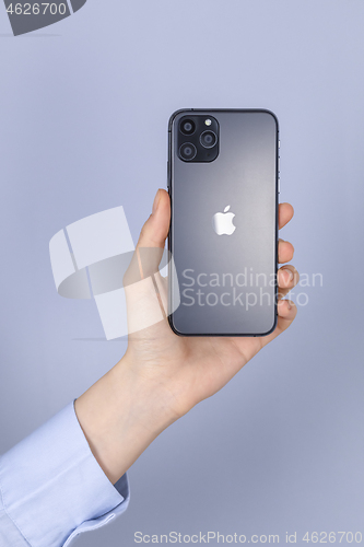 Image of Hand holding new iPhone 11 Pro on gray background