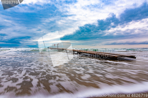 Image of Sea landscape with beautiful clouds in blue tones, with a pier on the horizon